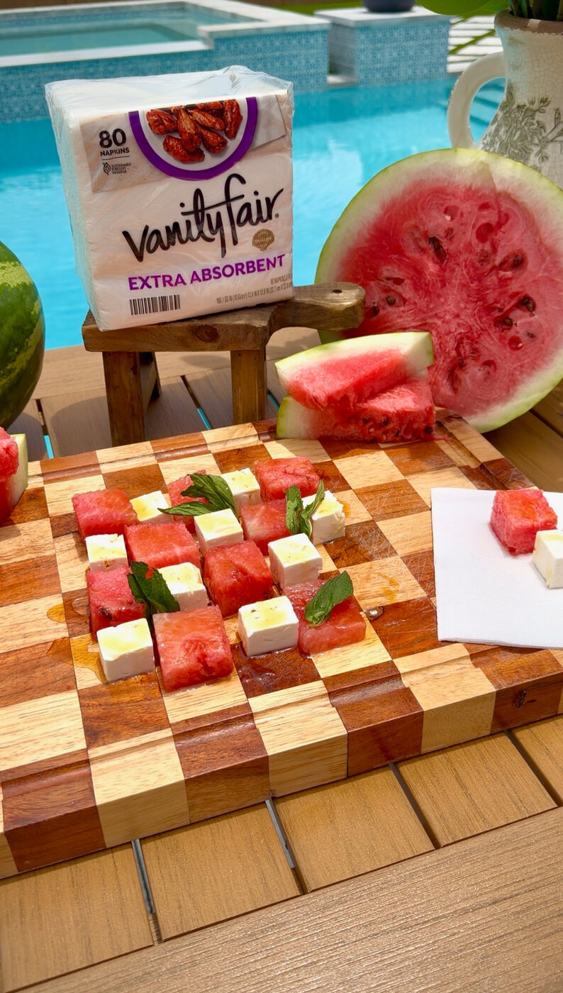 Watermelon and feta bites with mint on a checkerboard board by a pool