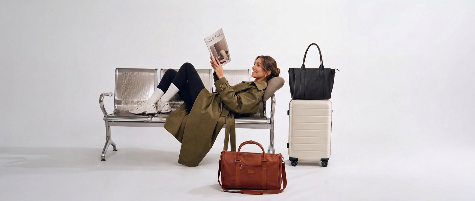 Laura reclining across airport seats reading a magazine beside her luggage